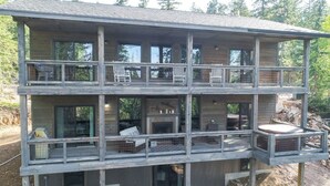 A two-story wooden cabin with multiple balconies, large windows, and a fireplace. - Lucky 7 Lodge – Spacious 4-Bedroom Cabin with Double Decks, Hot Tub & Mountain Views (Lead)