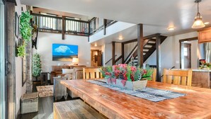 A spacious dining area with a wooden table, benches, and a decorative centerpiece. - Lucky 7 Lodge – Spacious 4-Bedroom Cabin with Double Decks, Hot Tub & Mountain Views (Lead)