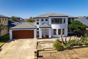 A two-story house with a garage, a covered porch, and a landscaped yard. - Seacrest Luxurious Holiday Home (Dalyellup)