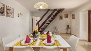 A dining area with a table set for two, a staircase in the background, and a small table with a plant. - House Papinka With Private Pool & Garden (Sveta Nedelja)