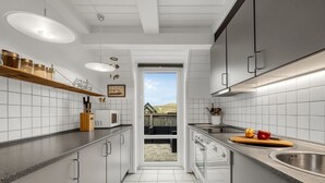 A modern kitchen with white cabinets, a black countertop, and a view to the outside. - "Kaja" - 150m from the sea by Interhome (Harboøre)