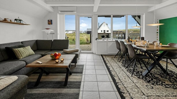 A modern living room with a grey sofa, a wooden coffee table, and a dining area with a green wall and a view of a house. - "Kaja" - 150m from the sea by Interhome (Harboøre)