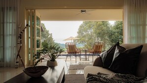 Een moderne woonkamer met een bank, een salontafel en uitzicht op een terras met stoelen en een tafel.