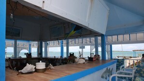 A bar area with a wooden counter, blue and white decor, and a view of the sea. - Exuma Beach Point (Rolleville)