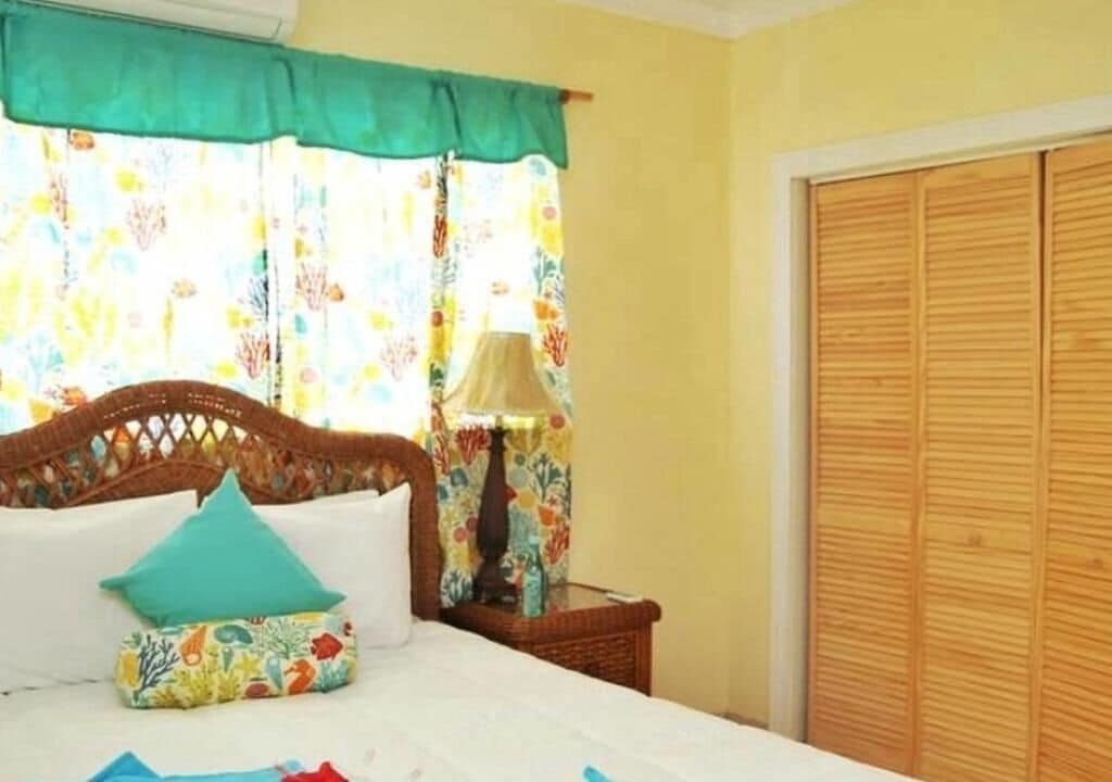 Quarto com uma cama, mesa de cabeceira, abajur e guarda-roupa.