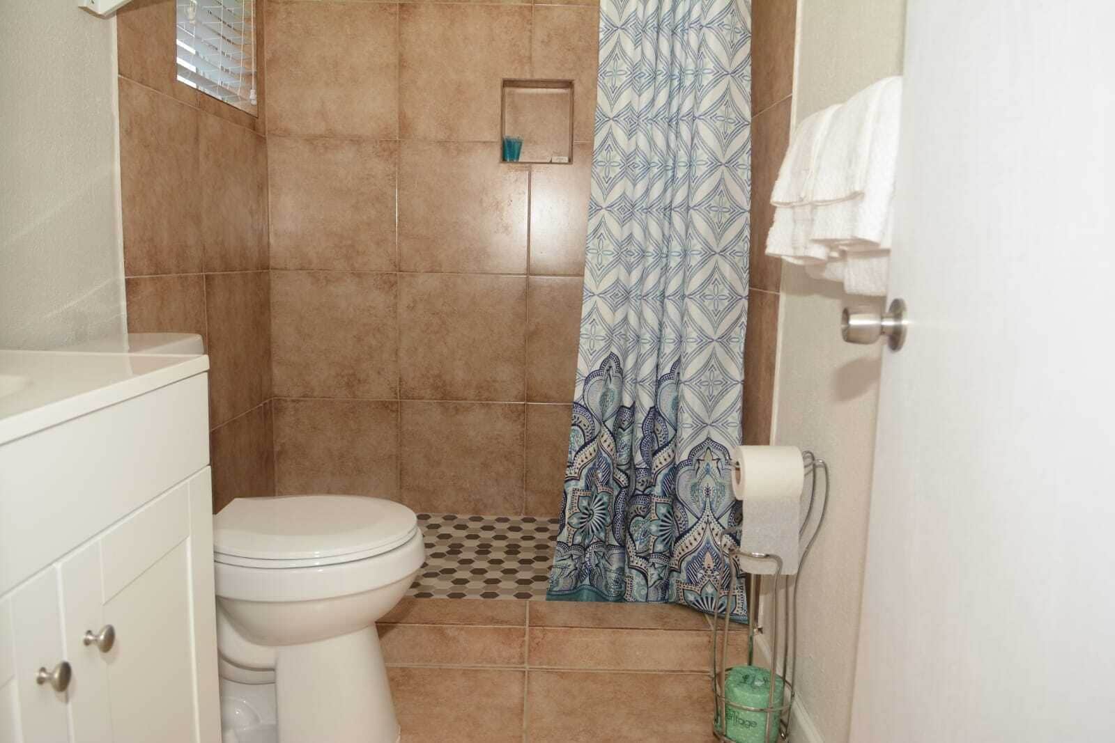 A bathroom with a toilet, a shower curtain, and a toilet paper holder.