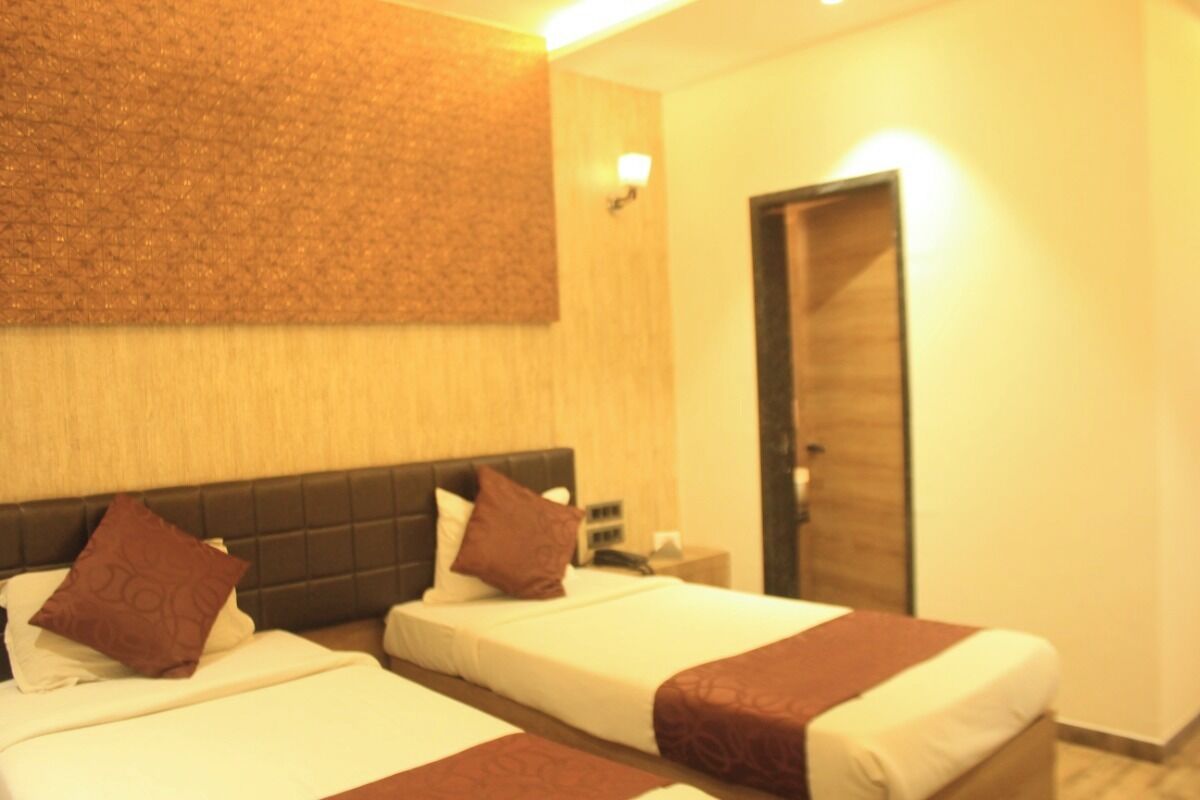 A hotel room with two beds, a wooden headboard, a wall-mounted light, and a door.