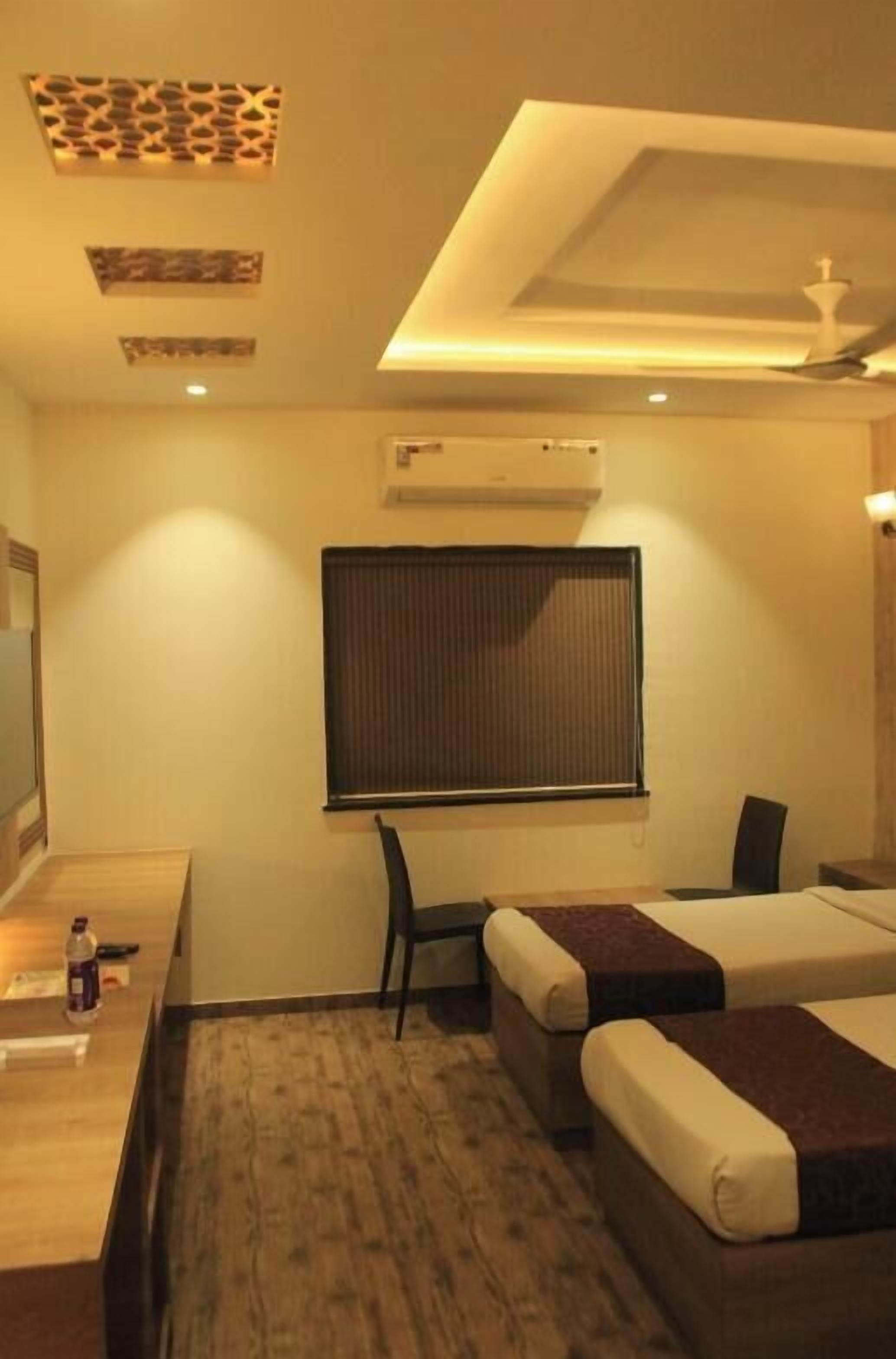 A hotel room with a bed, a desk, a chair, and a window with blinds.