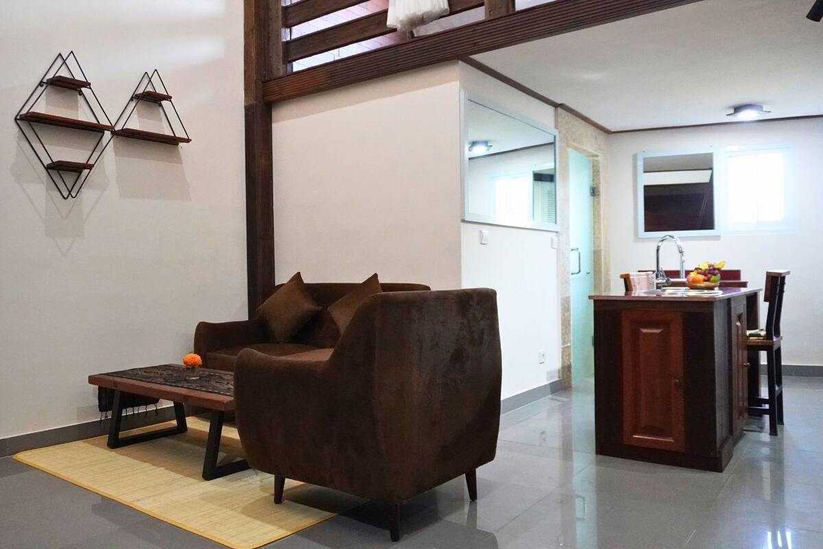 A living room with a brown sofa, a small table, and a decorative wall piece.