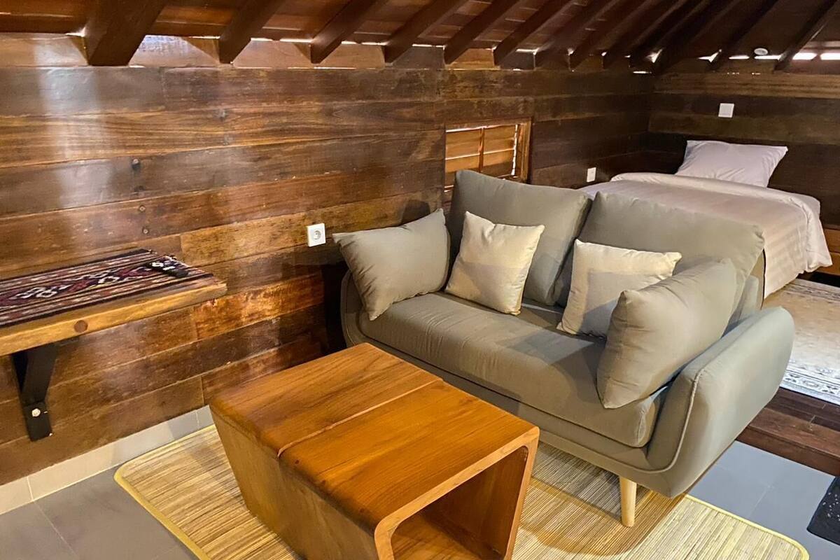 A cozy room with a wooden bench, a sofa with cushions, and a wooden coffee table.
