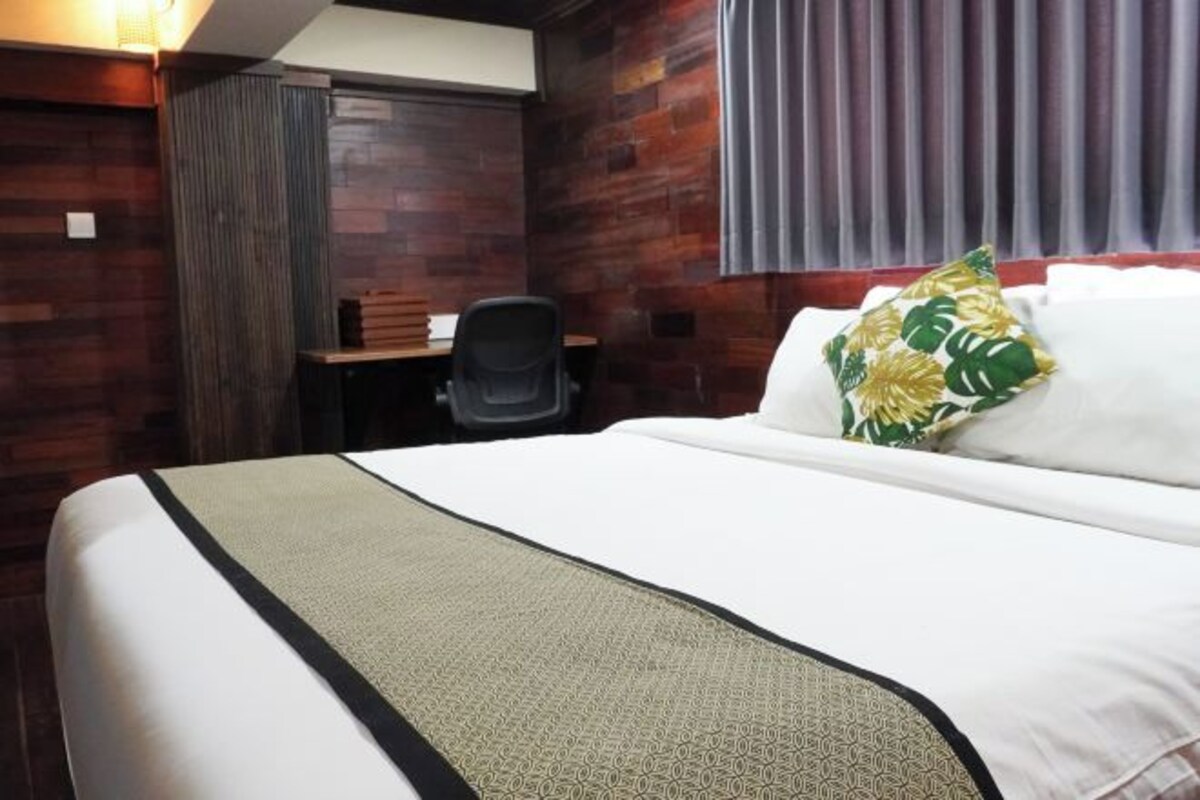 A hotel room with a large bed, a desk, and a chair.