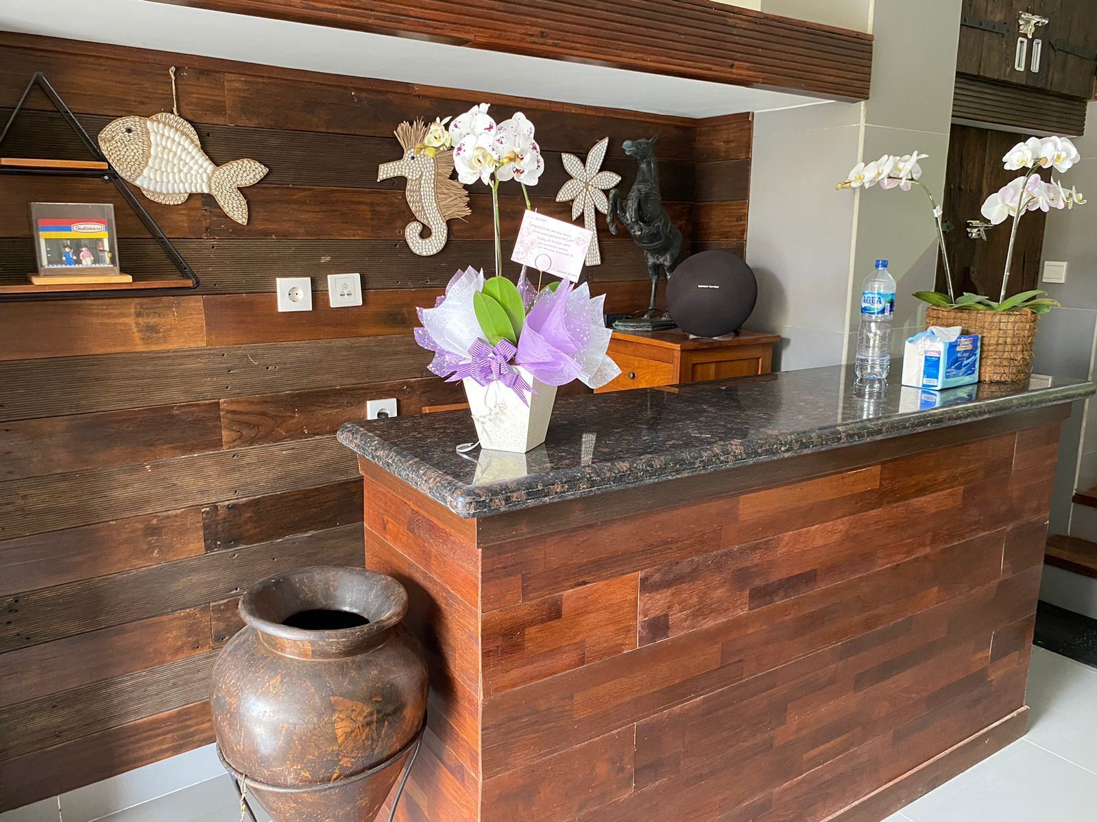 A reception desk with a wooden backdrop, a vase of flowers, and decorative items.