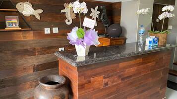 A reception desk with a wooden backdrop, a vase of flowers, and decorative items.