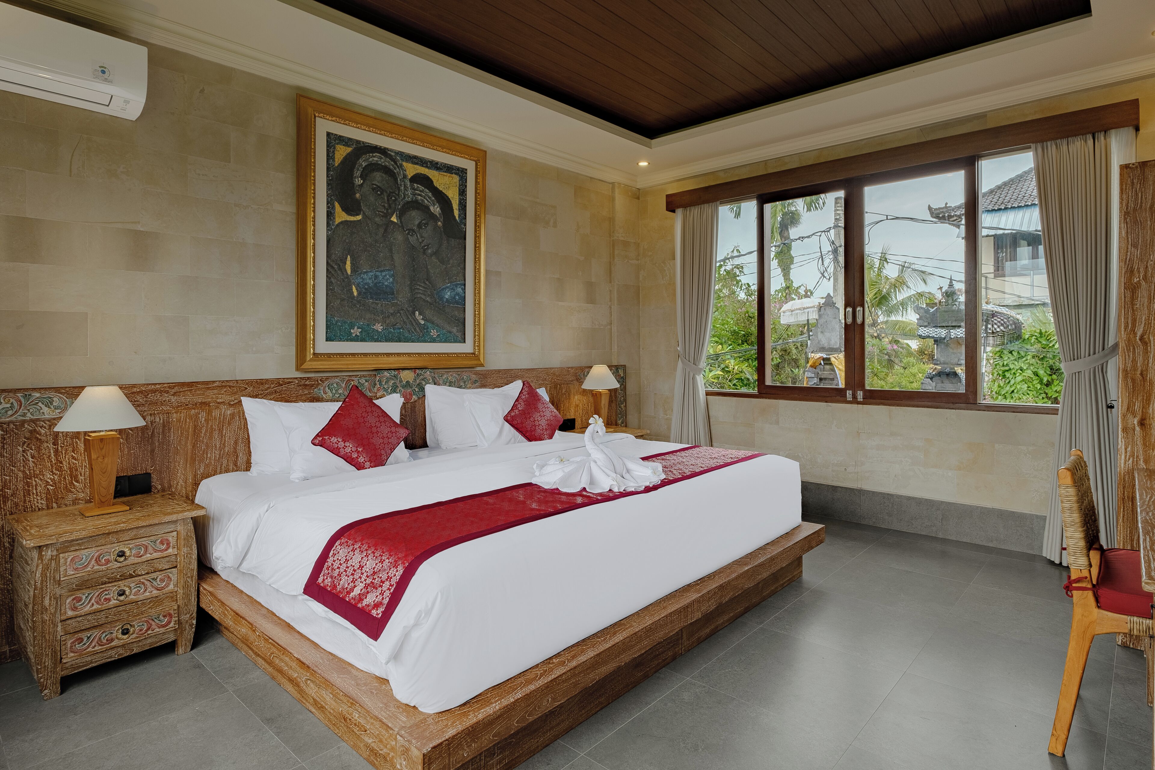 A spacious bedroom with a large bed, wooden headboard, and a view of the outside.
