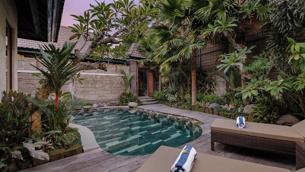 A swimming pool surrounded by lush greenery and a wooden deck. - Monique Ubud Villa (Ubud)