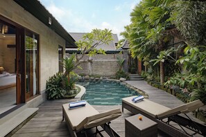 A pool area with lounge chairs and a stone wall. - Monique Ubud Villa (Ubud)