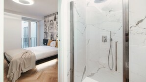 Een moderne badkamer met een douchecabine van glas en een slaapkamer met een bed en een balkon.