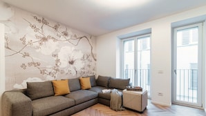 Een moderne woonkamer met een modulaire bank, een klein bijzettafeltje en een decoratief wandpaneel.