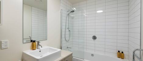 A modern bathroom with a white sink, mirror, and bathtub.