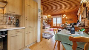 A wooden cabin interior with a kitchen, dining area, and living room.