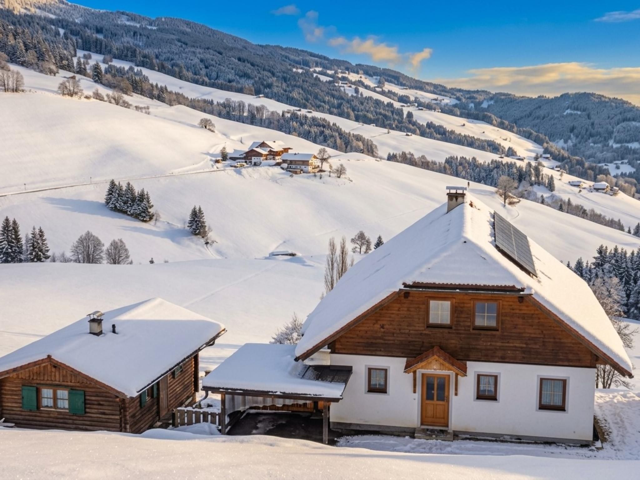 Une cabane en bois, dotée d’un toit en pente, entourée de champs et de montagnes enneigés.