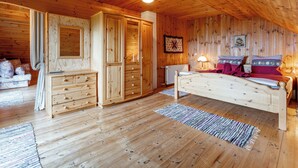 A wooden cabin interior with a bed, dresser, and a large mirror.