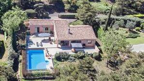 Ein zweistöckiges Haus mit Swimmingpool, umgeben von Grünflächen und Bäumen.
