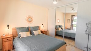 Ein Schlafzimmer mit Bett, Nachttischen, einem Spiegel und einer Wandleuchte.
