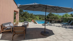 Eine Terrasse mit Gartenmöbeln, einem Pool und Blick auf die umliegende Landschaft.
