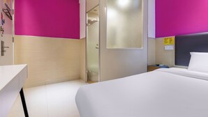 Een hotelkamer met een bed, een bureau, een badkamer en een douche.