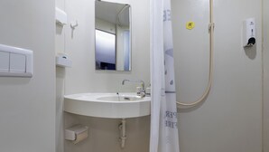 Een badkamer met wastafel, spiegel, handdoekhouder en douchegordijn.
