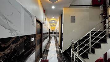 A hotel corridor with marble walls, a staircase, and a fire alarm.