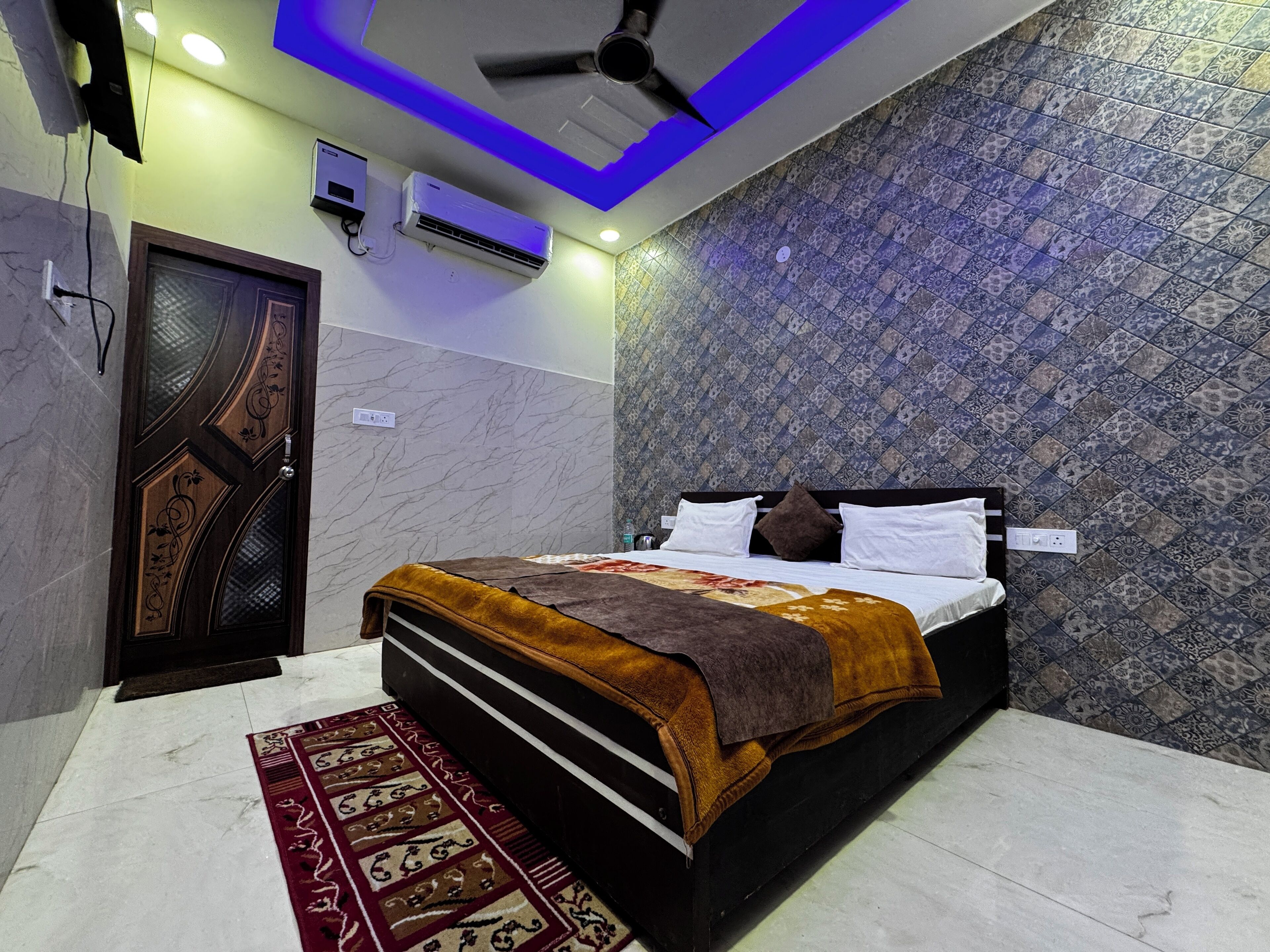 A bedroom with a bed, a ceiling fan, an air conditioning unit, and patterned walls.