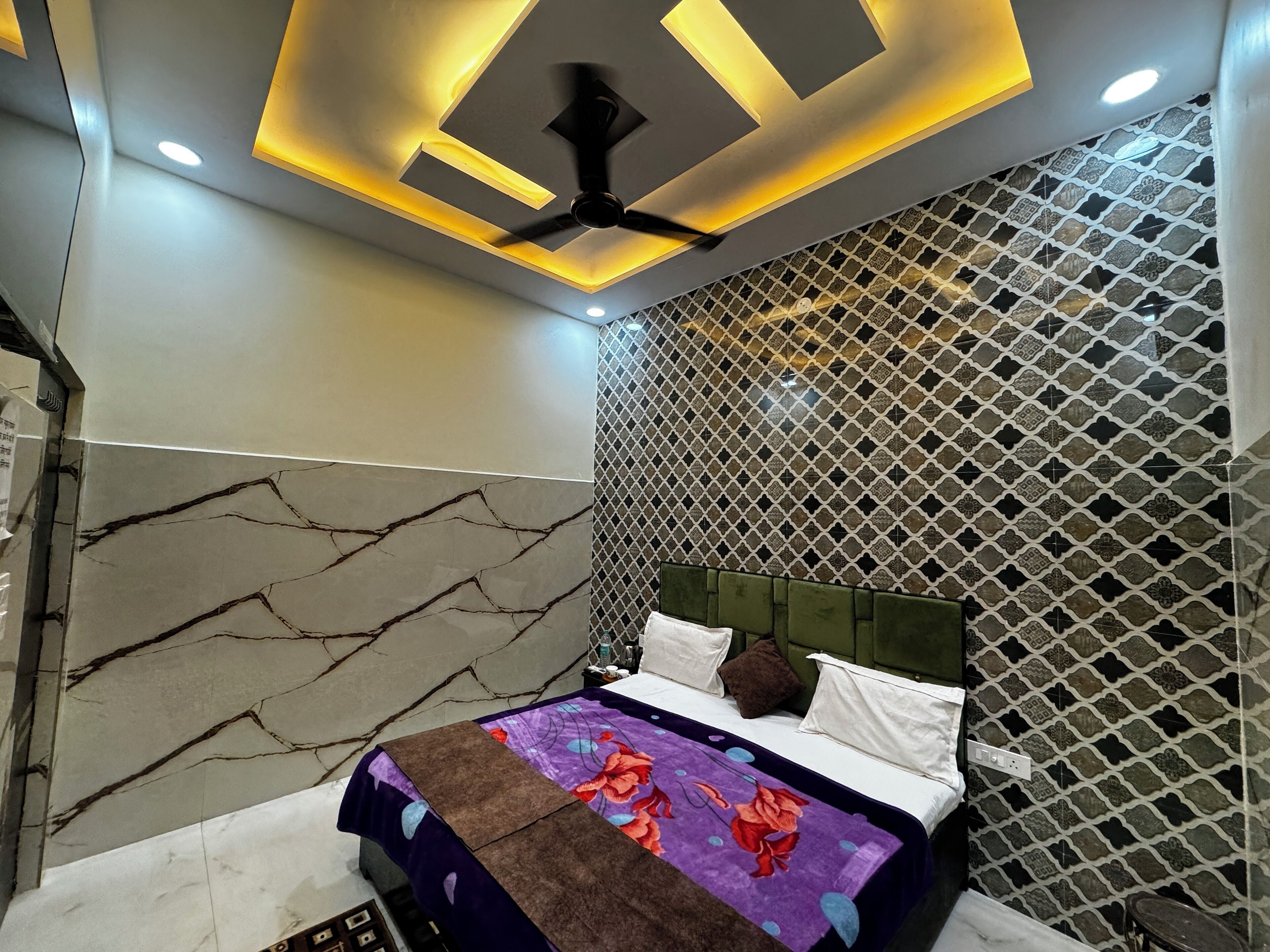 A bedroom with a bed, a ceiling fan, and a patterned wall.