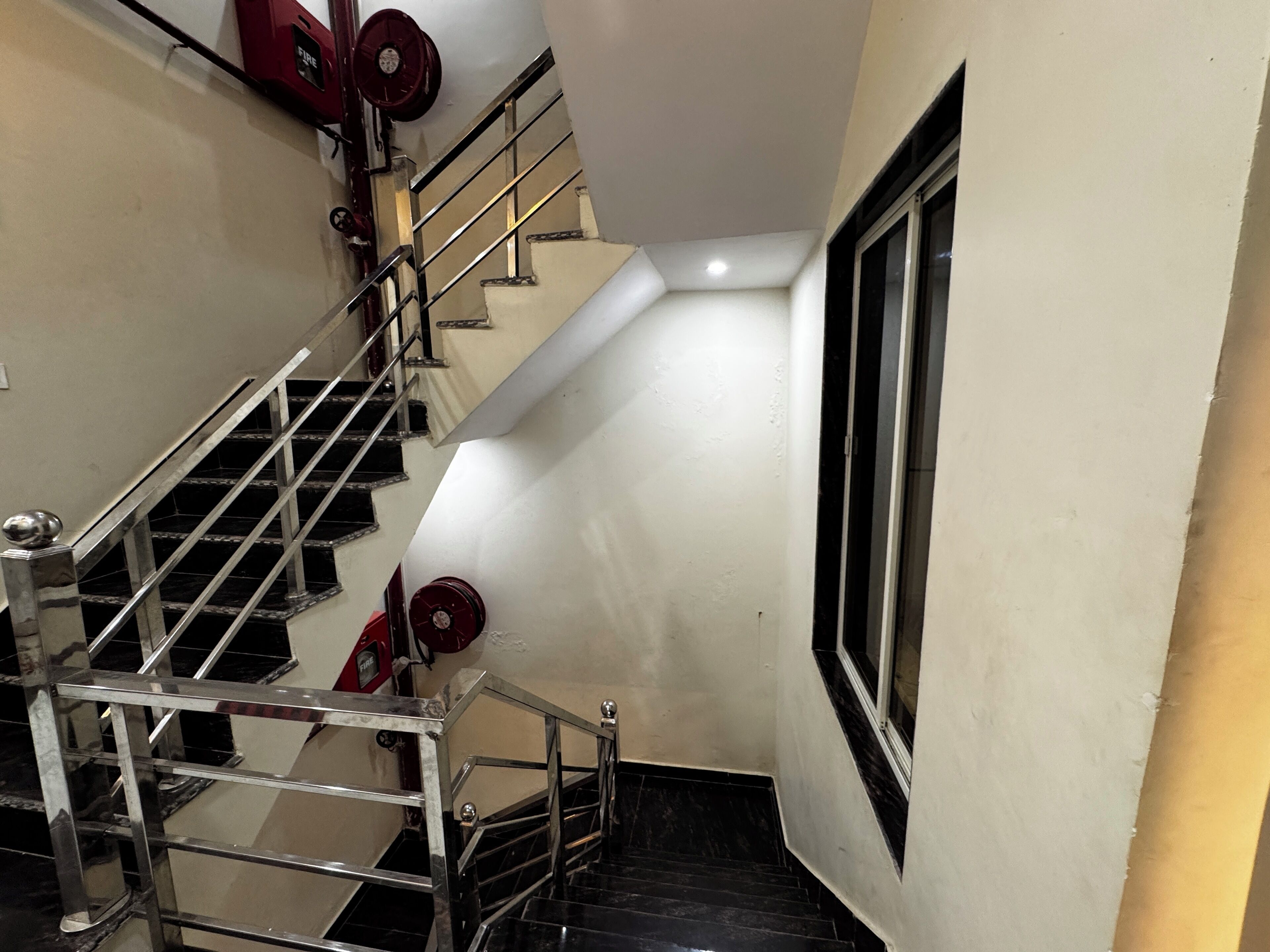 A staircase with metal railings and a red fire alarm.