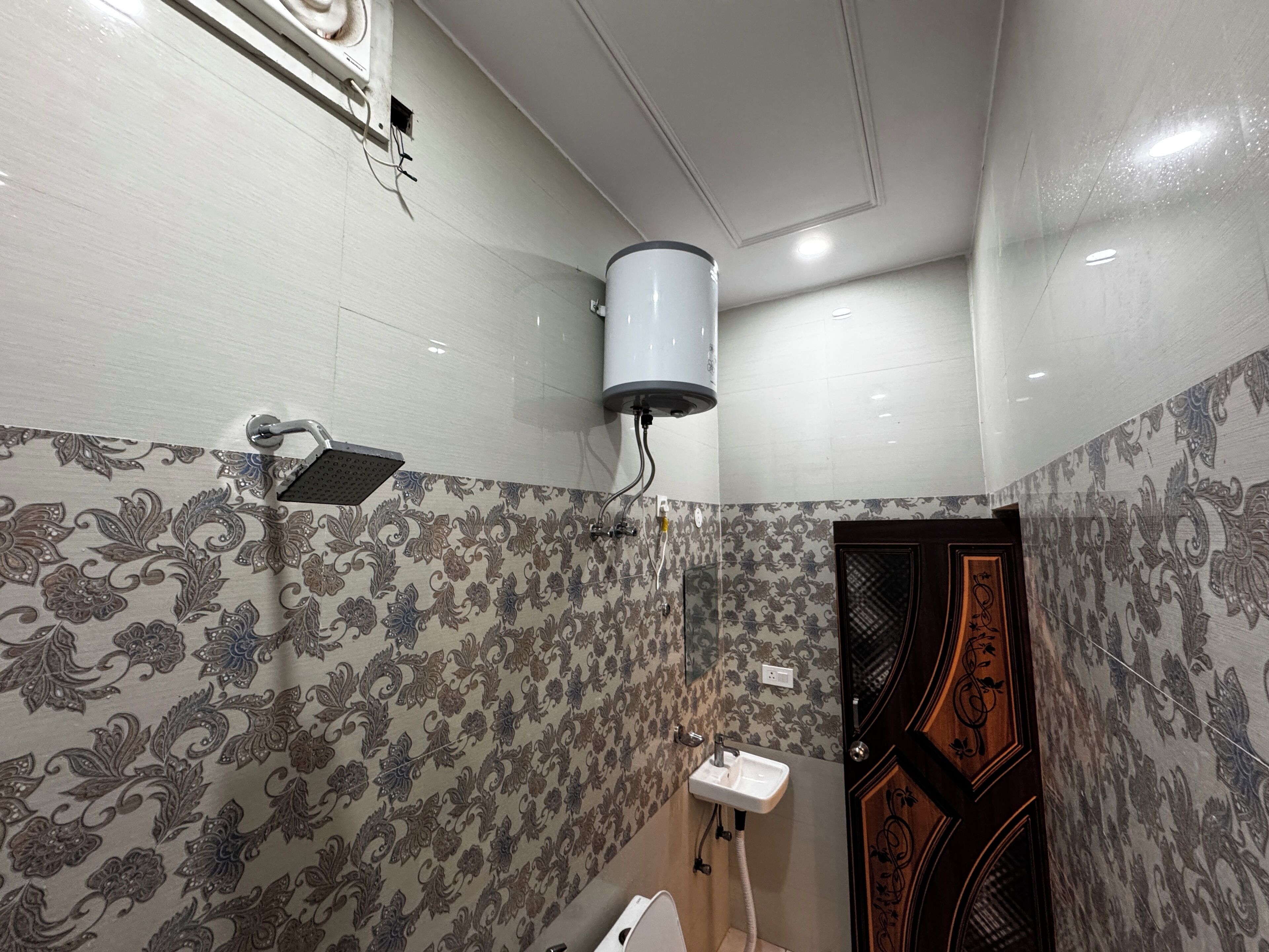 A bathroom with patterned wallpaper, a white sink, and a toilet.