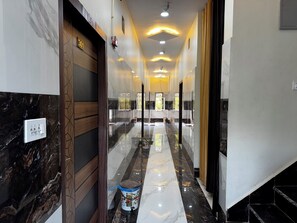 A hallway with a marble floor, a wooden door, and a glass partition. - Vrindavani Kunj (Vrindavan)