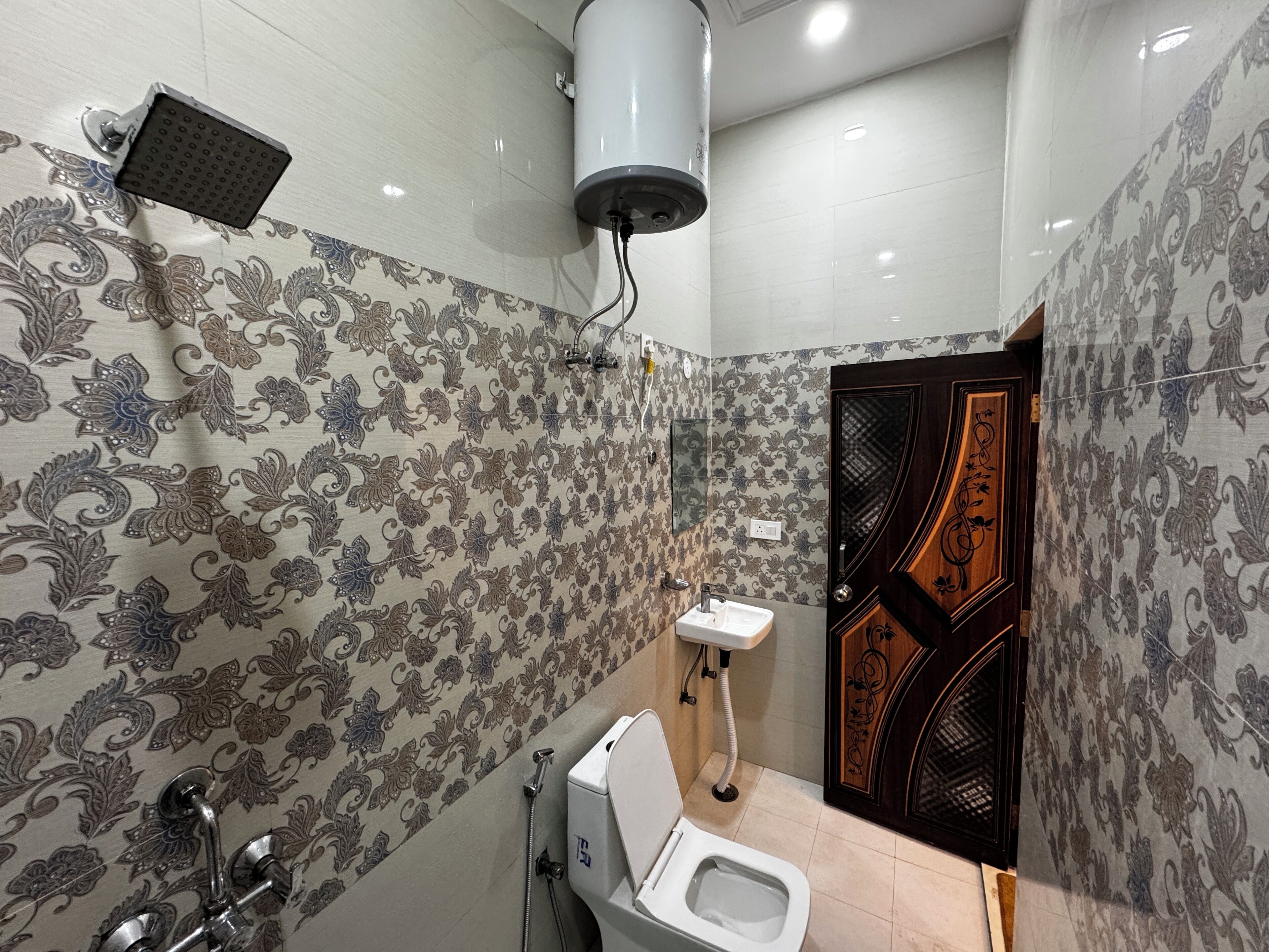 A bathroom with patterned wallpaper, a toilet, a sink, and a shower.