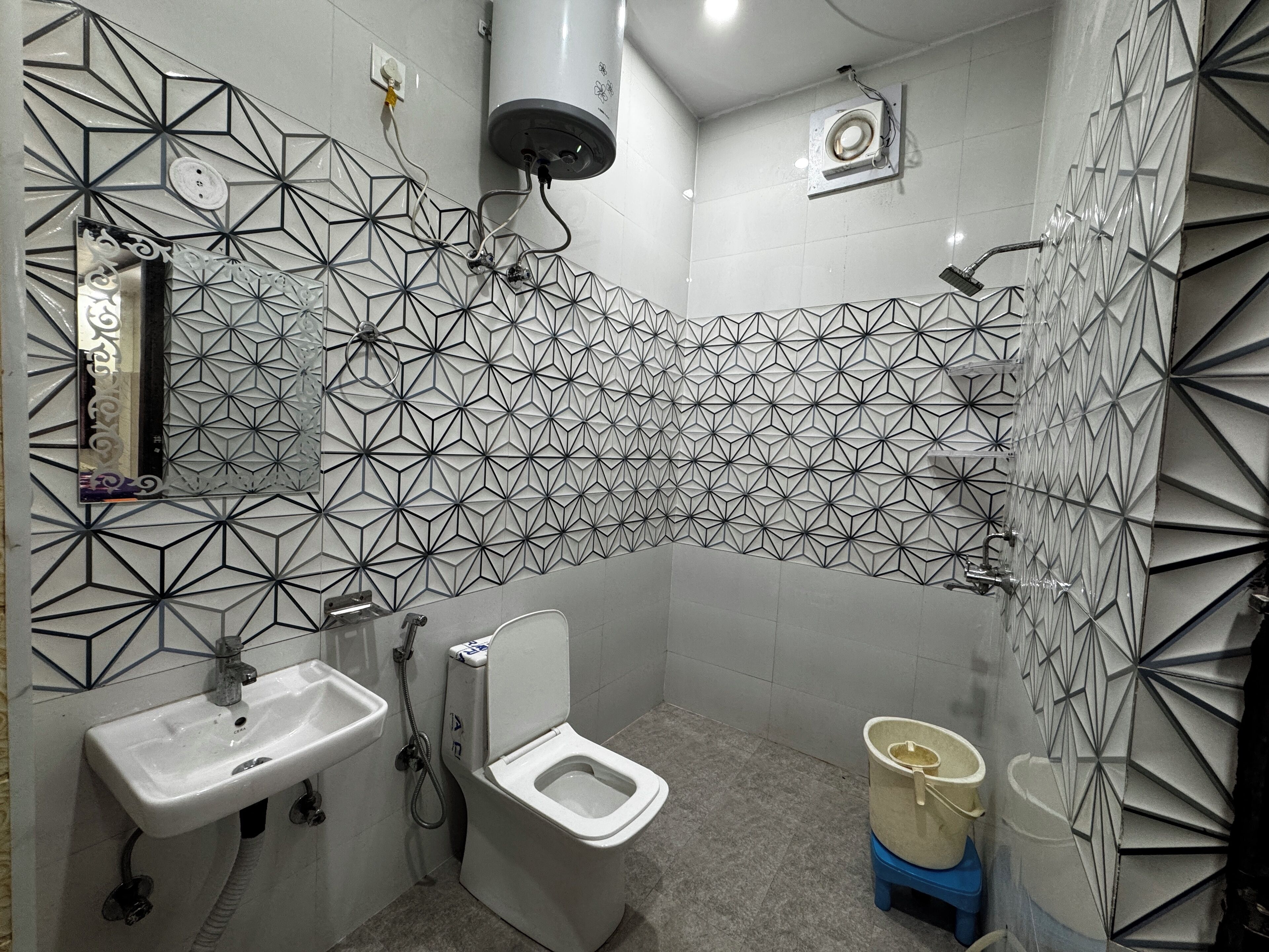 A bathroom with a geometric tile backsplash, a sink, a toilet, and a shower.