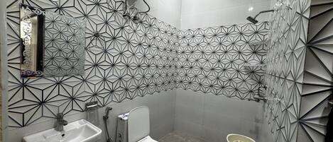 A bathroom with a geometric tile backsplash, a sink, a toilet, and a shower.