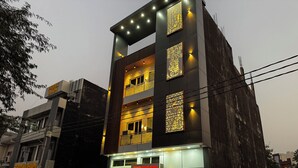 Un edificio a più piani dal design moderno, con pannelli illuminati e una targa con su scritto 'Priya Dhani'.