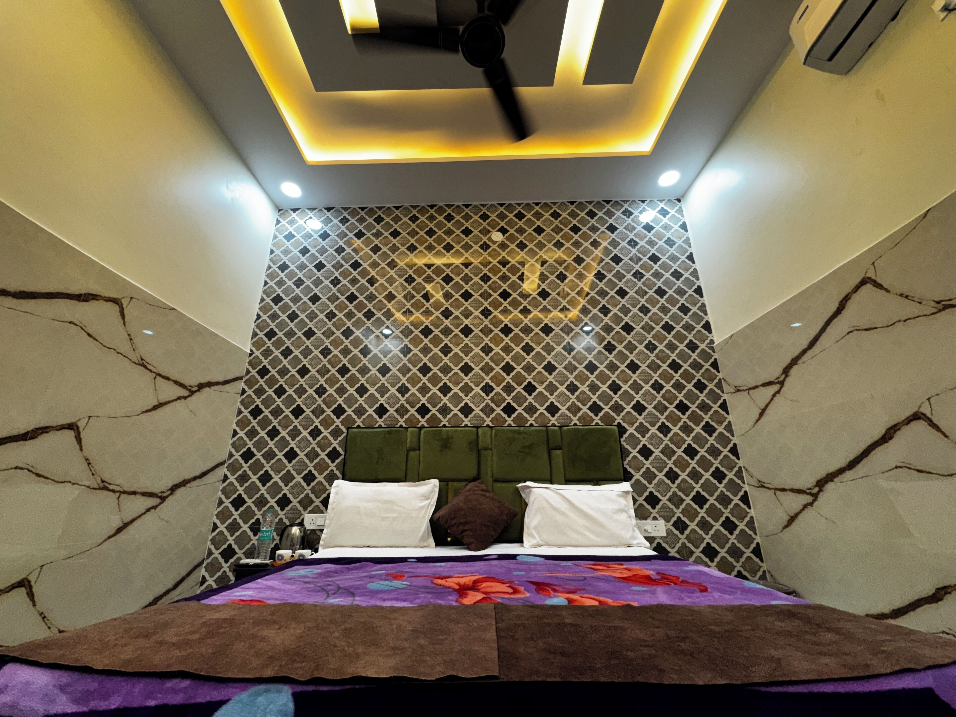 Une chambre à coucher avec un lit, un ventilateur de plafond et un mur décoré de motifs.