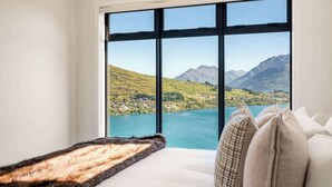 A room with a large window offering a view of a lake and mountains.