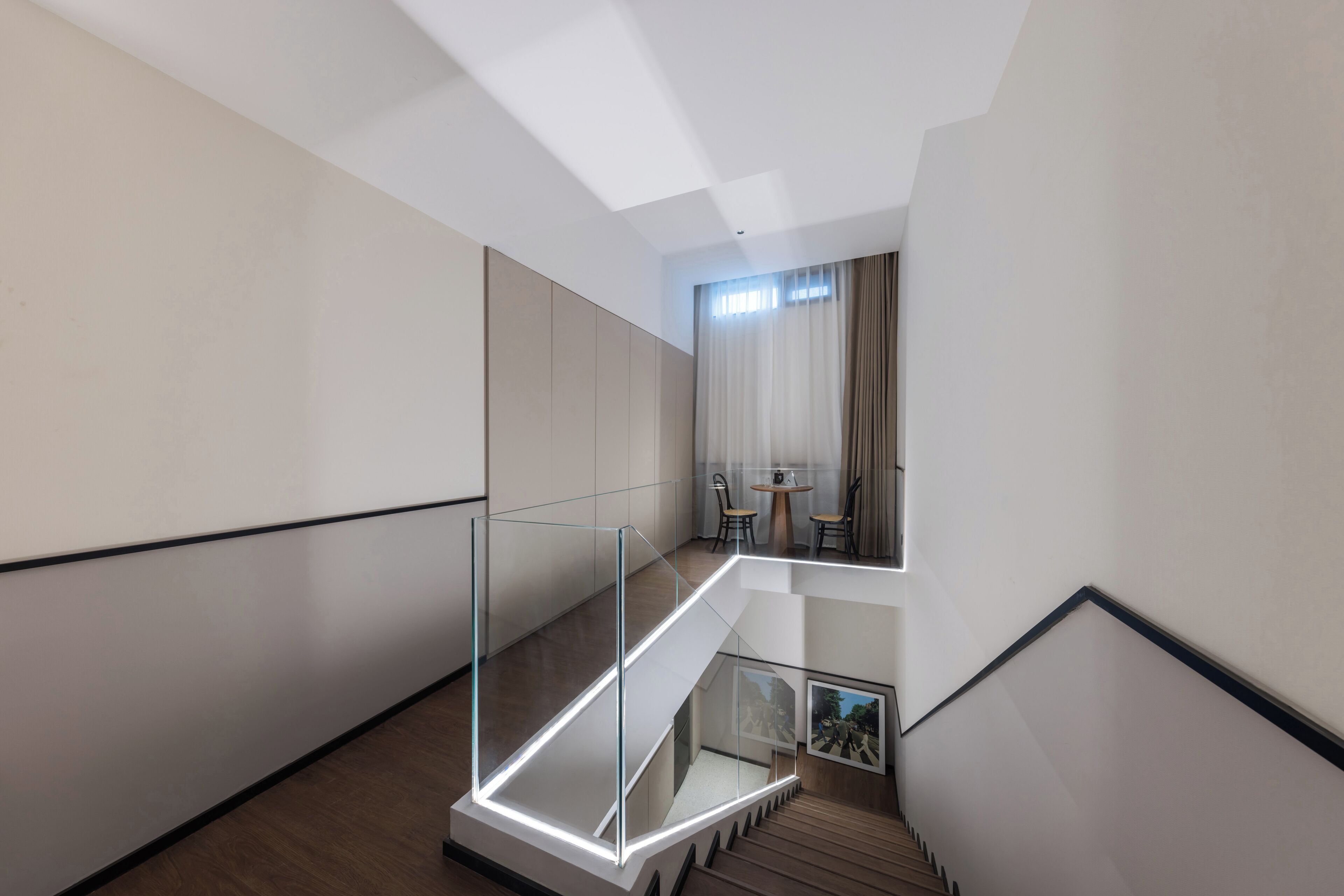 A modern interior with a glass staircase leading to a dining area.