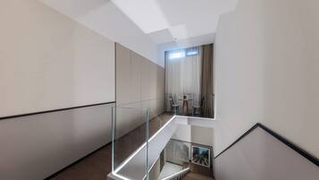 A modern interior with a glass staircase leading to a dining area.