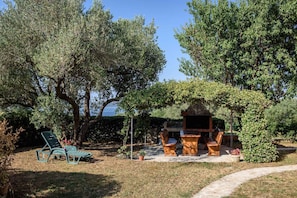 A patio area with a barbecue setup, outdoor furniture, and a stone pathway. - Apartments in Kozino/zadar Riviera 7951 (Zadar)