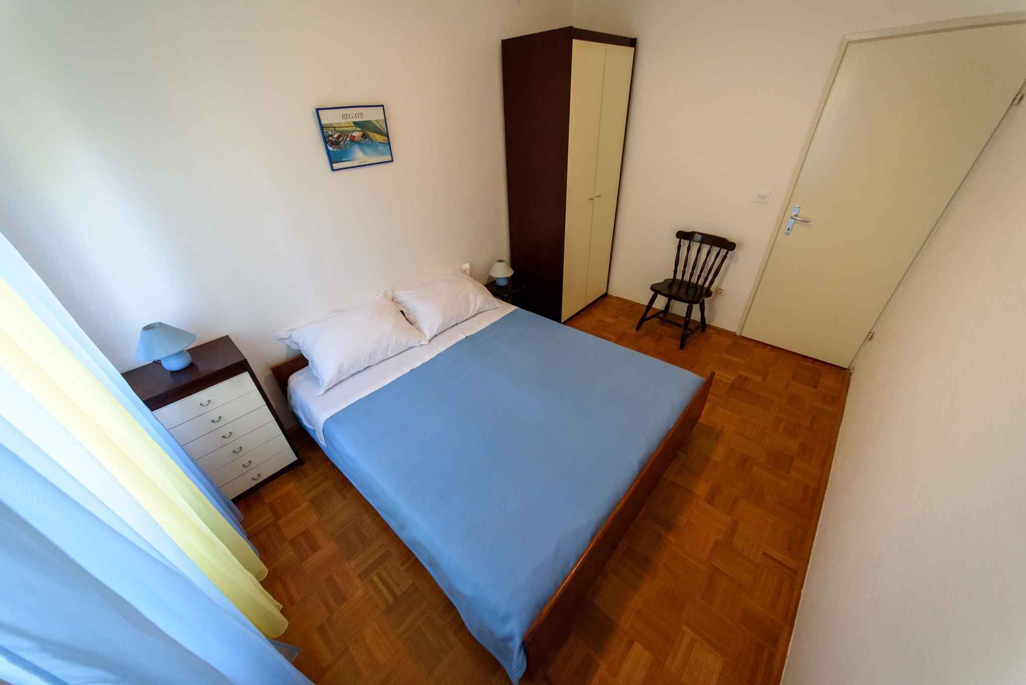 Ein Schlafzimmer mit einem Bett, einem Schrank, einem Sessel und einem Nachttisch.