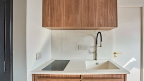 A modern kitchen with wooden cabinets, a stainless steel sink, and a black countertop. - New Apartment Center of Paris/le Marais (Paris)