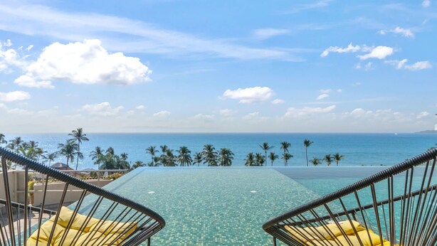 Ein Pool mit freiem Blick auf den Ozean und Palmen.