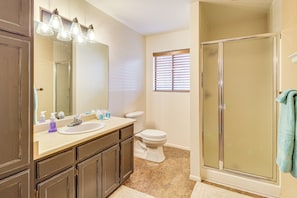 Une salle de bain équipée d’un lavabo, d’un miroir, de toilettes et d’une douche.